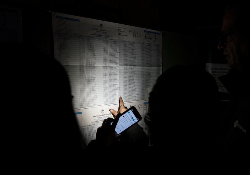 People look for their names in a voters list at a polling station during a national blackout in Rosario, Santa Fe, Argentina.  Reuters
