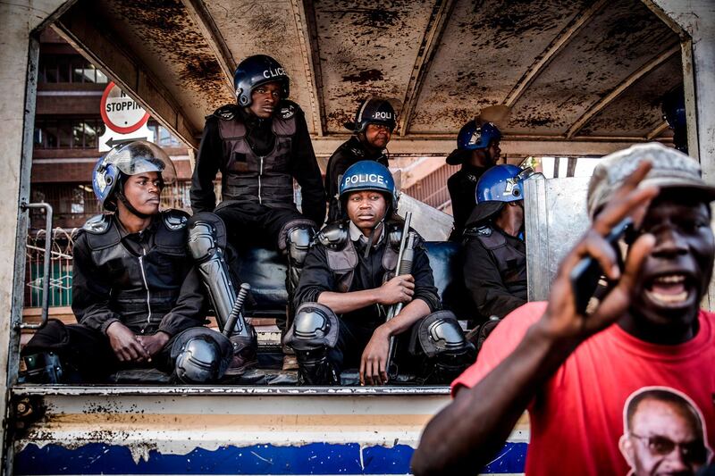 Zimbabwean anti riot police officers sit in a truck, look at a supporter of the opposition party Movement for Democratic Change (MDC) who takes part in a protest. AFP