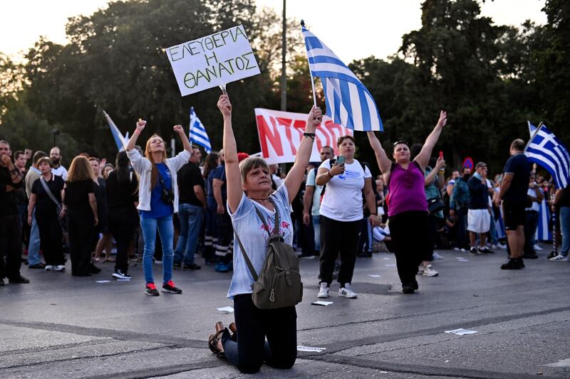A Greek anti-vaccine protester sits on her knees during a rally in the northern city of Thessaloniki where Prime Minister Kyriakos Mitsotakis was to deliver a speech. AP