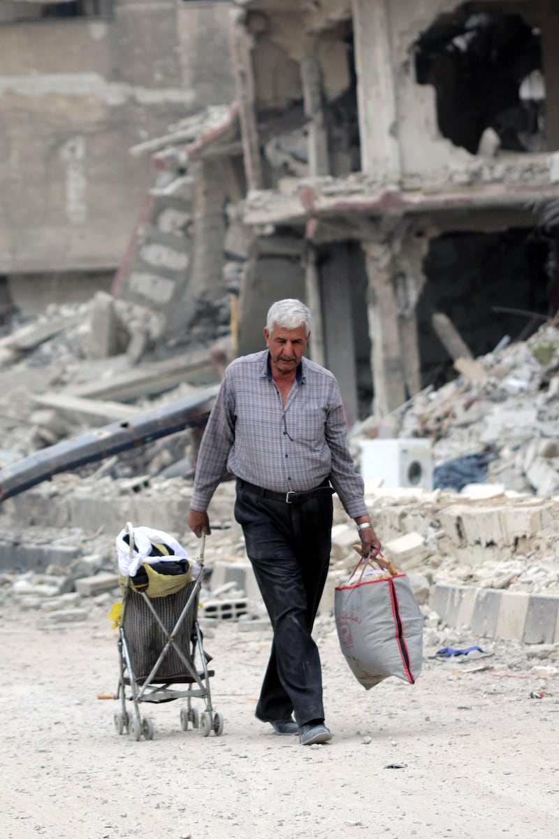 epa06755989 A man carries belongings and walk at the Yarmouk Camp district in south Damascus, Syria, 22 May 2018. Media reports state the Syrian government of Bashar al-Assad on 21 May recaptured the last area of Damascus under opposition control and took full control of the capital for the first time since the outbreak of the civil war in 2011, after groups of Islamic State (IS) fighters holed up in an area of south Damascus, including the Palestinian refugee camp Yarmouk, were bussed out.  EPA/YOUSSEF BADAWI