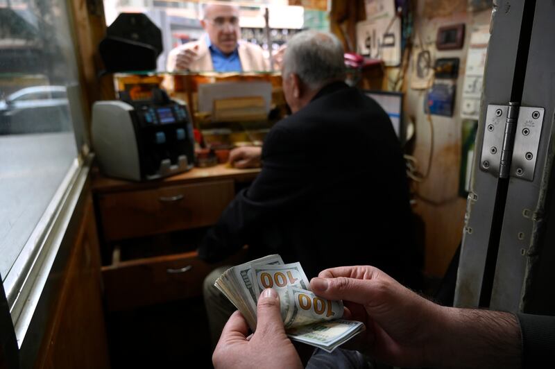 A currency trader counts US banknotes at an exchange shop in Beirut. EPA