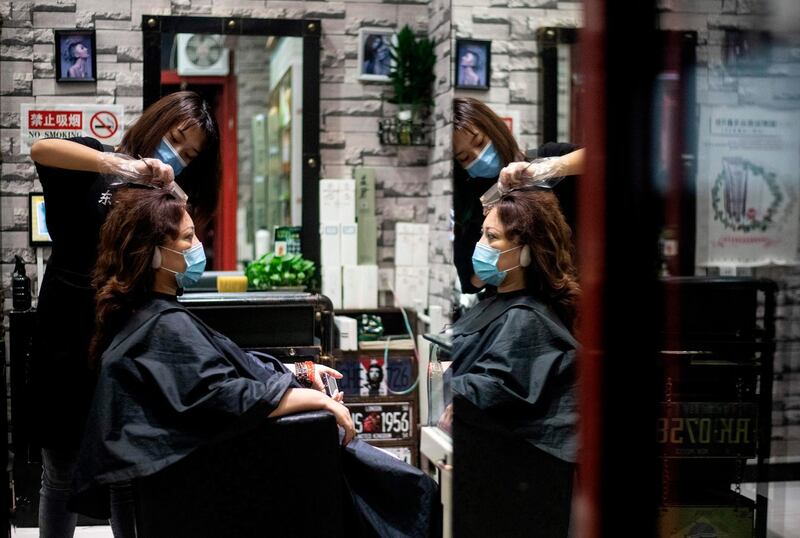 A hairdresser wearing a face mask gives a haircut to a customer at a beauty salon in Beijing.  AFP