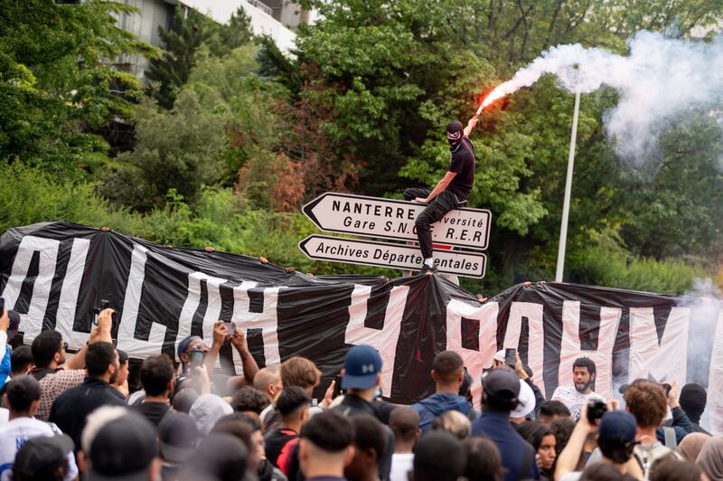 A protester waves a flare from a road sign during a march after the shooting of Nahel, 17. Bloomberg