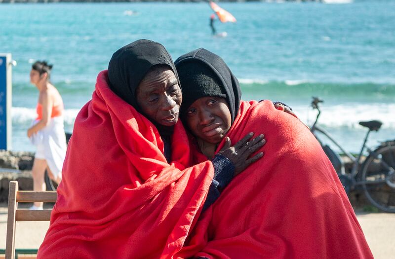 Two migrants rest on a beach after arriving at the coast of Teguise in Lanzarote island on December 26. EPA