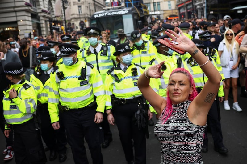 Police officers stand guard as demonstrators dance in London. Reuters
