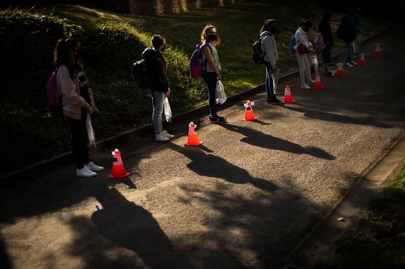 Students stand next to cones to mark social distancing as they wait in line before entering the classroom at Les Magnolias primary school during the partial lifting of COVID-19, lockdown regulations in Brussel.  AP Photo
