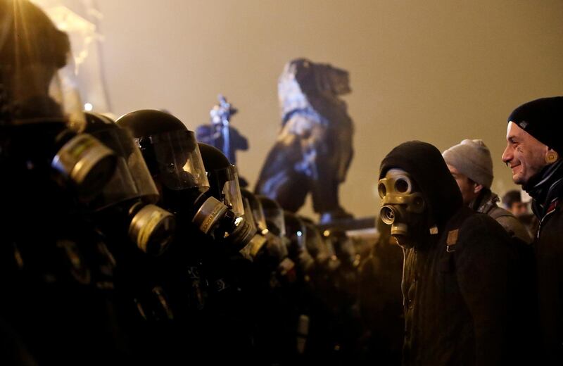 A demonstrator wearing a gas mask looks at policeman standing guard during a protest against the new labour law outside the Parliament building in Budapest, Hungary. Reuters