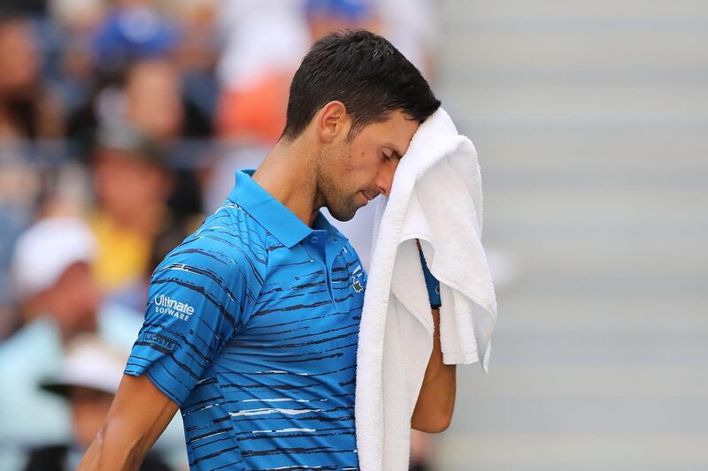 Novak Djokovic wipes away sweat during his match at a hot humid Arthur Ashes Stadium. AFP