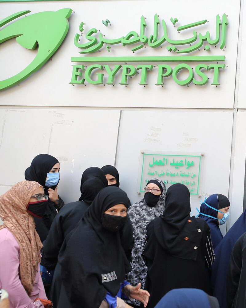 Egyptians wearing protective face masks stand outside a post office in Cairo, Egypt. EPA