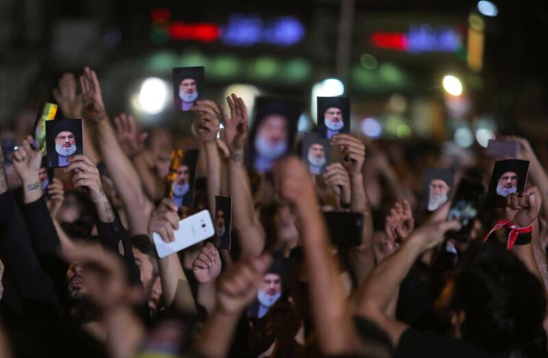 Hezbollah supporters hold photographs of leader  Hassan Nasrallah during his address in Beirut. Khalil Hasan / Reuters