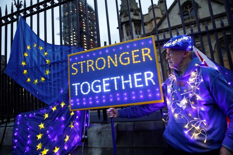 An anti-Brexit protester displays illuminated EU flags near the Houses of Parliament in London. AFP