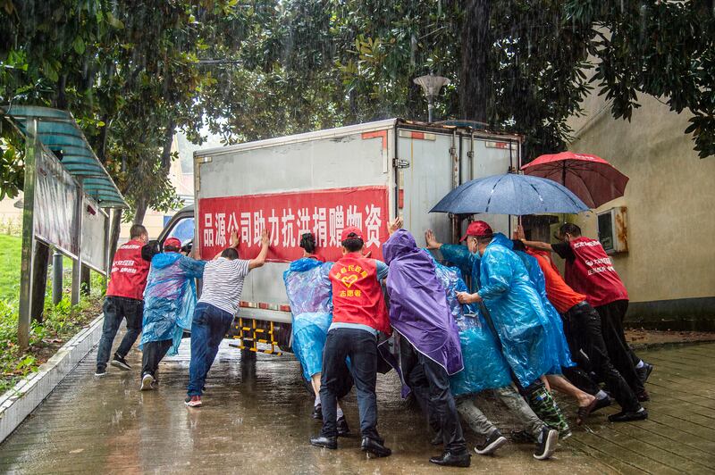 Residents and emergency relief workers push a van loaded with supplies in Liulin township, Suixian county, in central China's Hubei province.