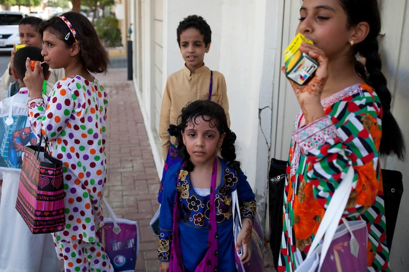 Sharjah, United Arab Emirates - June 23 2013 - (L-R) Noora Al Suwaidi, 8, Abdullah Al Jabri, 9, Maitha Al Jabri and Hind Al Suwaidi,10, take a moment before entering a home in the Leyyah neighborhood of the city. They are participating in Hag El Leila, an Emirati tradition that occurs every year 15 days before the start of the month of Ramadan. The tradition involves children walking from door-to-door singing and collecting sweets and money. (Razan Alzayani / The National)  FOR RYM GHAZAL STORY  *** Local Caption ***  RA0623_hag_el_layla_012.jpg