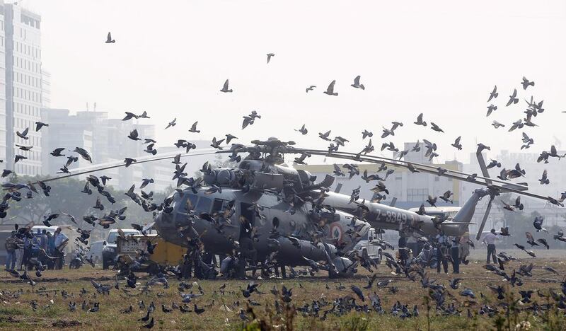 Pigeons fly after an Indian Air Force helicopter which made an emergency landing at the Bandra Kurla complex ground in Mumbai.  Rajanish Kakade / AP Photo