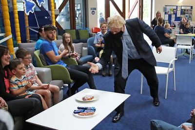 LOSSIEMOUTH, SCOTLAND - JULY 23: Prime Minister Boris Johnson prepares to help himself to a Tunnock's teacake whilst meeting families at the community centre at RAF Lossiemouth, Moray, during a visit to the Highlands and Northern Isles of Scotland on July 23, 2020 in Lossiemouth, Scotland. This week marks one year as U.K. Prime Minister for Conservative Party leader Boris Johnson. Today he is visiting businesses in the Orkney Islands in Scotland to reaffirm his commitment to supporting all parts of the UK through the Coronavirus pandemic. Later he will visit a military base in Moray to thank Military personnel for their service. (Photo by Andrew Milligan - WPA Pool/Getty Images)