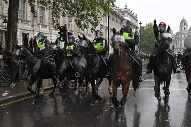 Mounted police officers charge their horses along Whitehall, past the entrance to Downing Street, in an attempt to disperse protesters. AFP