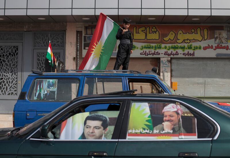 FILE - In this, Sept. 25, 2017 file photo, a boy carries a Kurdish flag on top of a car with pictures of Kurdish president Masoud Barzani and his son Masrour on the windows, in the disputed city of Kirkuk, Iraq.  The office of Iraq's parliament speaker says Salim Jabouri is traveling to the country's Kurdish region to meet with Barzani, Sundaay, Oct. 8, 2017. The move comes in the wake of the Kurdish regional vote for independence in a controversial referendum two weeks ago. (AP Photo/Bram Janssen, File)