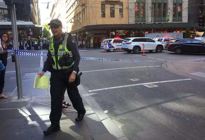 Police officers secure the area as members of the public stand behind police tape after the arrest of the driver of a vehicle that ran into pedestrians at a crowded intersection in central Melbourne on Thursday. Melanie Burton / Reuters