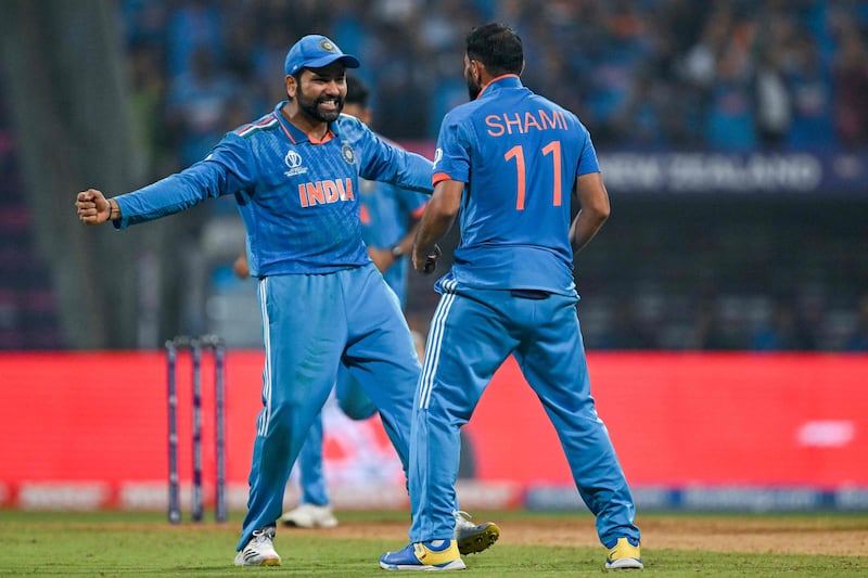 India's captain Rohit Sharma celebrates with teammate Mohammed Shami after the dismissal of New Zealand's Tom Latham. AFP