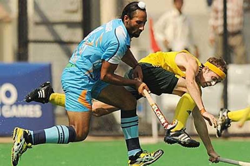 India’s Sardar Singh, left, tackles Australian hockey player Matthew Swann. Australia won the gold medal with a resounding 8-0 victory yesterday.