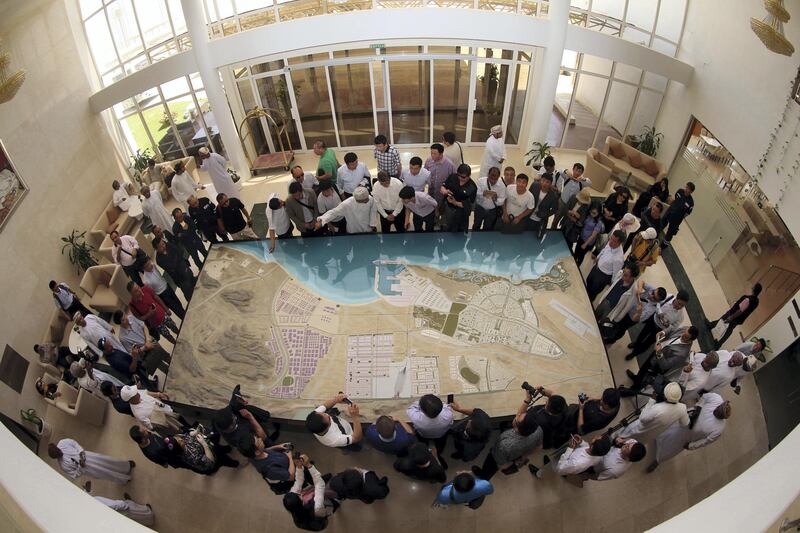A picture taken with a fish-eye lens shows Chinese investors listening to an explanation as they check the model of the dry dock which is to be built following an economic agreement, on May 24, 2016 in the Omani port city of Duqm.
Chinese investors signed a deal with Oman's government to establish an industrial city, including an oil refinery, in the port town of Duqm, both sides said in a joint statement. The agreement signed during the ceremony in Muscat would open way for investments worth $10.7 billion by 2022 to finance industrial projects in Duqm, on the Arabian Sea, which the Omani government is developing in a bid to diversify revenues beyond oil. / AFP PHOTO / MOHAMMED MAHJOUB