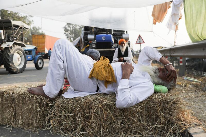 A farmer rests on a stack of hay at a site of a protest against the newly passed farm bills at Singhu border near Delhi, India.  Reuters