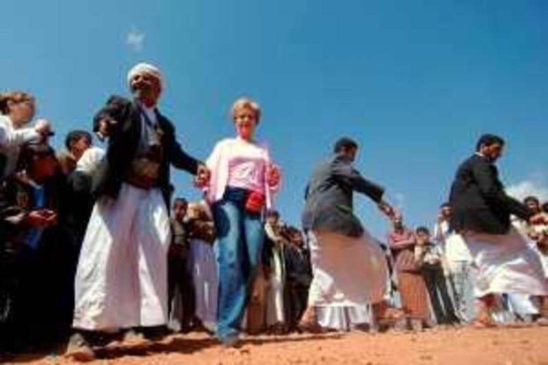 A foreign woman dances with Yemeni men at the touristic area of Wadi al-Daher, on the outskirts of Sanaa, on February 13, 2010. Calm prevailed in northern Yemen on the second day of a shaky truce between government forces and Shiite rebels that broke into deadly violence hours after it went into effect, both sides said.   AFP PHOTO/MOHAMED HUWAIS