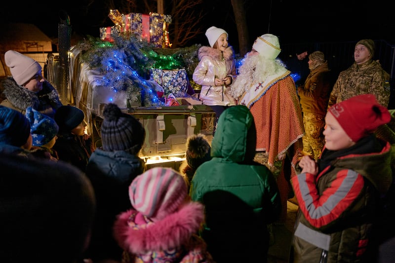 Children receive presents from a Ukrainian soldier dressed as Santa on Christmas Eve 2022 in Sloviansk. Getty Images