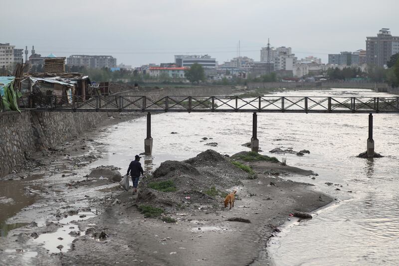 An Afghan man walks next to the Kabul river after the rain