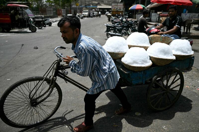 A worker carries baskets of shaved ice to a food processing unit at a market in New Delhi. AFP