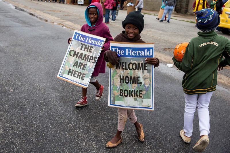 Children hold two posters as they wait for the start of the parade of the South African Rugby World Cup winner with their Web Ellis Trophy, in Kwazakhele. AFP