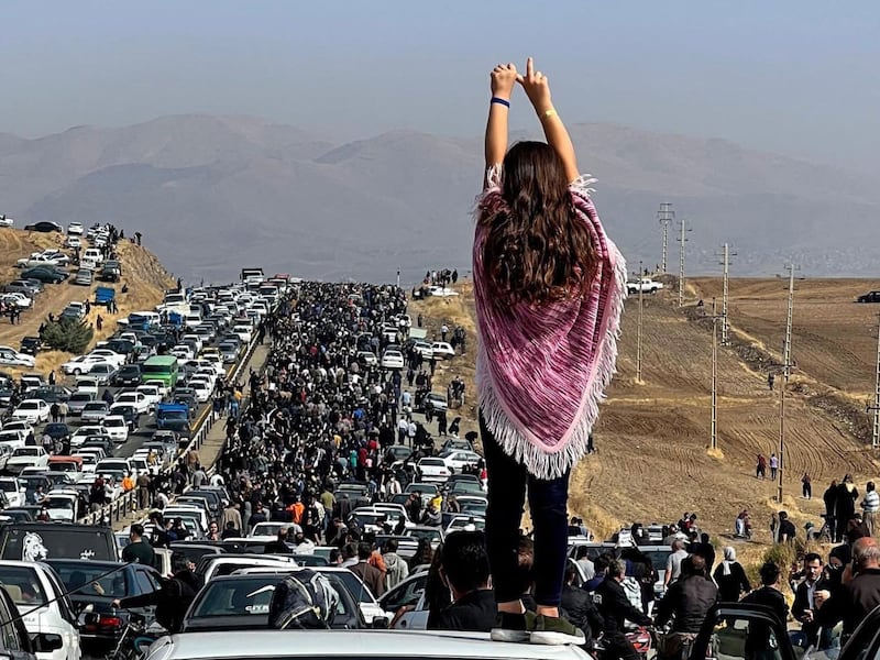 A woman not wearing a headscarf stands on top of a vehicle as thousands make their way towards Saqez, Mahsa Amini's home town, to mark 40 days since her death in police custody. AFP