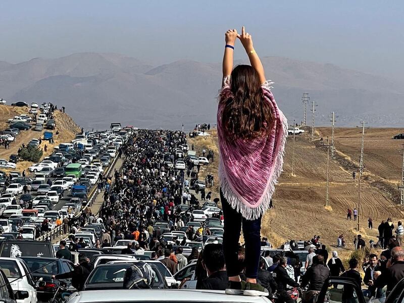 A woman not wearing a headscarf stands on top of a vehicle as thousands make their way towards Saqez, Mahsa Amini's home town, to mark 40 days since her death in police custody. AFP