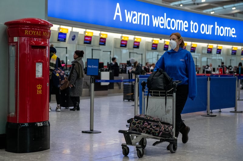 An airline passenger wearing a face mask pushes her bags through Heathrow's Terminal 5 during the coronavirus pandemic in 2020