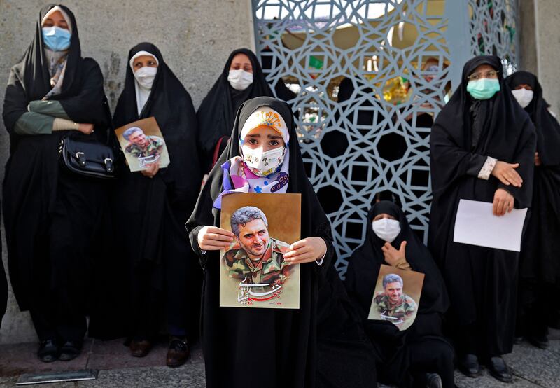 Iranian women lift portraits of Col Hassan Sayad Khodai during his funeral in Tehran. AFP