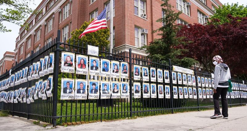 A woman looks at pictures of the graduating senior class hung on the fence at a high school in New York. EPA