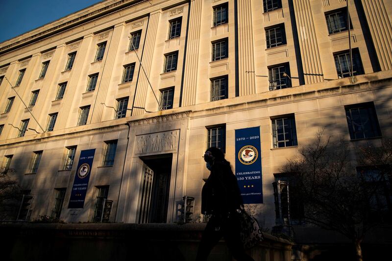 FILE PHOTO: A woman walks past the U.S. Department of Justice Building, in Washington, U.S., December 15, 2020. REUTERS/Al Drago/File Photo