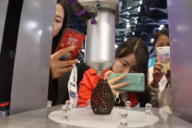 Visitors take photos of a 3D printer working a pattern with chocolate during the 10th Global Mobile Internet Conference in Beijing, China, on April 26, 2018.  Wu Hong / EPA