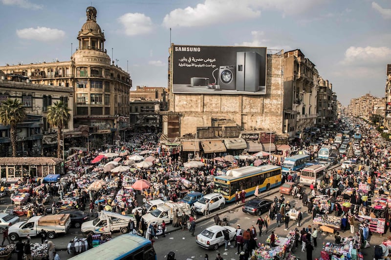 This picture taken on February 22, 2021 shows a view of vehicles stuck in a traffic jam amidst street vendors and pedlars in the central Attaba district of Egypt's capital Cairo. In gridlocked and heavily polluted Cairo, startups are searching for technological solutions to solve the transport headaches for an expanding megacity already struggling with over 20 million people. Cairo, the most populous Arab city where a fifth of all Egyptians live, is ranked 30th worst in the world for congestion, according TomTom, the Dutch vehicle navigations systems maker. / AFP / Khaled DESOUKI
