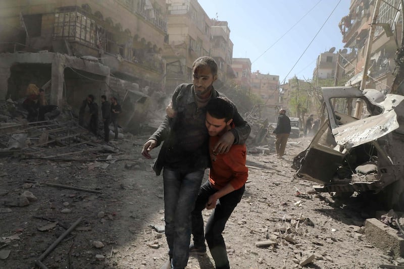 A Syrian man helps evacuate an injured victim following Syrian government air strikes on the Eastern Ghouta rebel-held enclave of Douma, on the outskirts of the capital Damascus on March 20, 2018. AFP