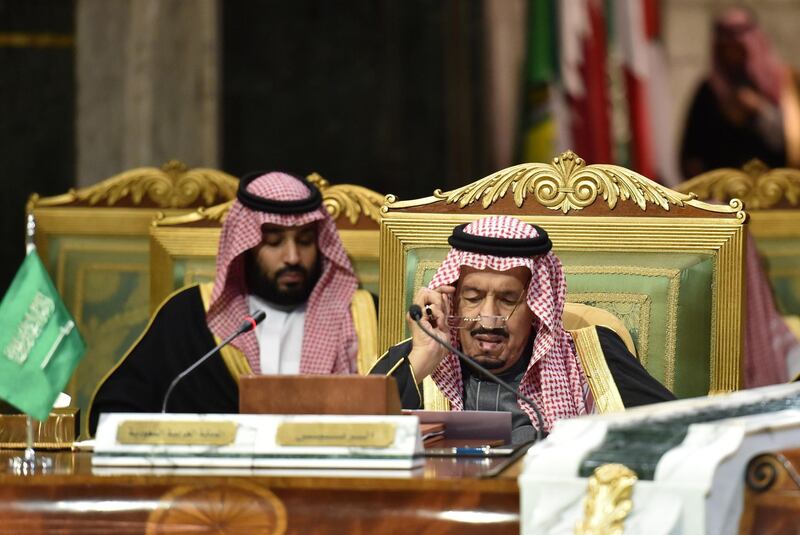 Saudi King Salman bin Abdulaziz, flanked by his son Crown Prince Mohammed bin Salman, puts on his spectacles as he prepares to read a document while chairing a session of the Gulf Cooperation Council summit. AFP / Fayez Nureldine