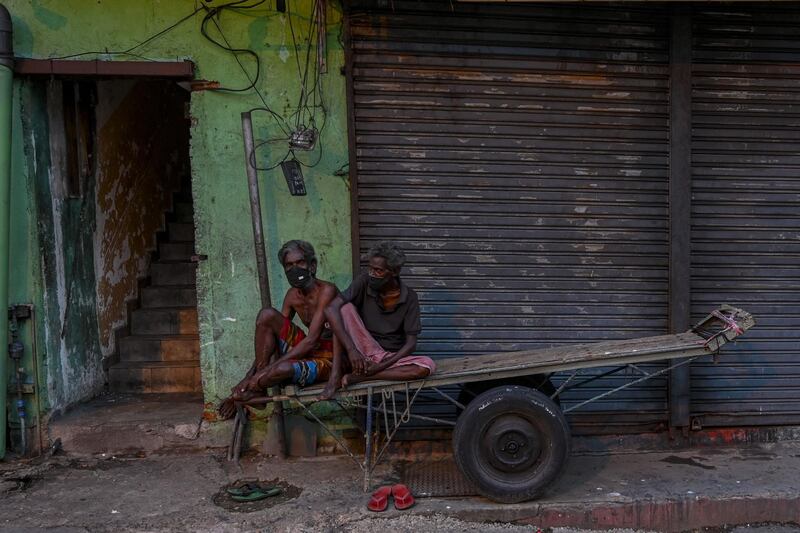 Men sit on a handcart along a street during a government imposed travel restrictions and weekend lockdown to curb the spread of Covid-19 coronavirus in Colombo. AFP