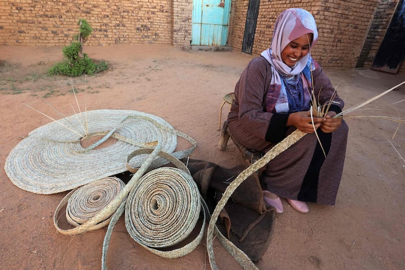 A Sudanese woman weaves palm leaves (al-Zaaf), a traditional skill of making baskets, food trays and other household items, in the village of Al-Saqqai, some 57km north of the capital Khartoum, on January 4, 2023.  (Photo by ASHRAF SHAZLY  /  AFP)
