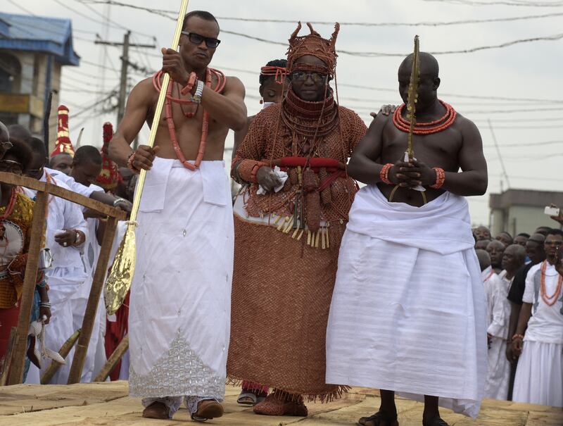 The king of Nigeria's Benin kingdom, Oba Ewuare II, centre, walks on a wooden bridge assisted by palace aides during his coronation in Nigeria in 2016. The Oba has played a key role in fighting trafficking gangs that use spiritual rituals to enslave victims. Photo: AFP