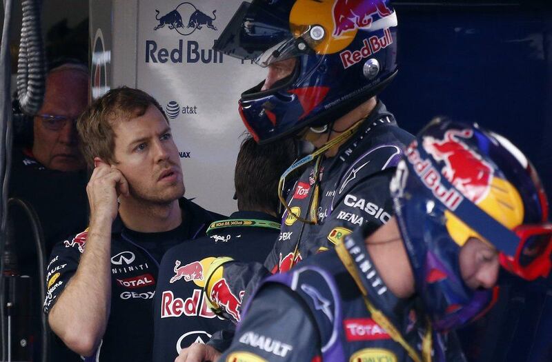 Red Bull Formula One team driver Sebastian Vettel, left, of Germany watches a television screen after retiring from the race during the Formula One Australian Grand Prix in Melbourne on March 16, 2014. AFP PHOTO / David Gray 