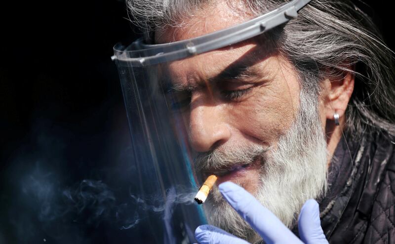 A man smokes a cigarette through a face shield during a protest organized by members of the restaurant industry against the coronavirus disease restrictions in Johannesburg, South Africa. Reuters