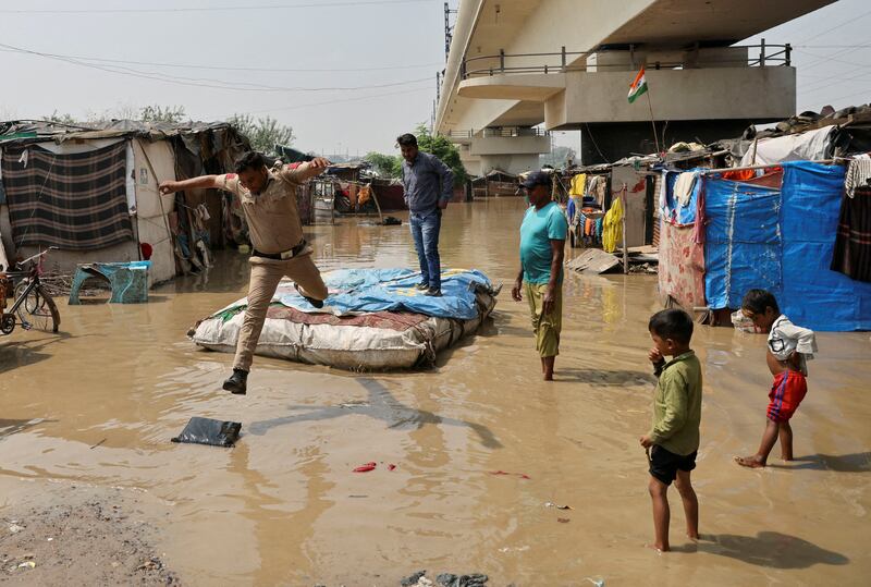 A policeman jumps off a makeshift raft after wading through a flooded area of a slum on the banks of the river Yamuna in New Delhi, India. Reuters