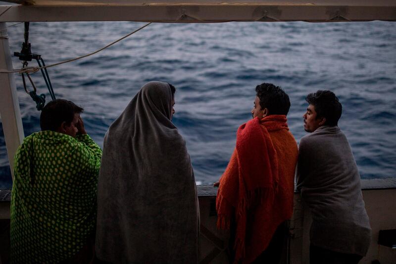 TOPSHOT - Migrants look at the sea from the deck of the boat of the NGO Proactiva Open Arms on July 1, 2018. A Spanish NGO said on June 30 it had rescued 59 migrants as they tried to cross the Mediterranean from Libya and would dock in Barcelona in Spain after Italy and Malta refused access. The news comes a day after three babies were found dead and 100 more went missing in a shipwreck off Libya that Proactiva Open Arms, whose charity rescue boat was in the area, said could potentially have been avoided.
 / AFP / Olmo Calvo
