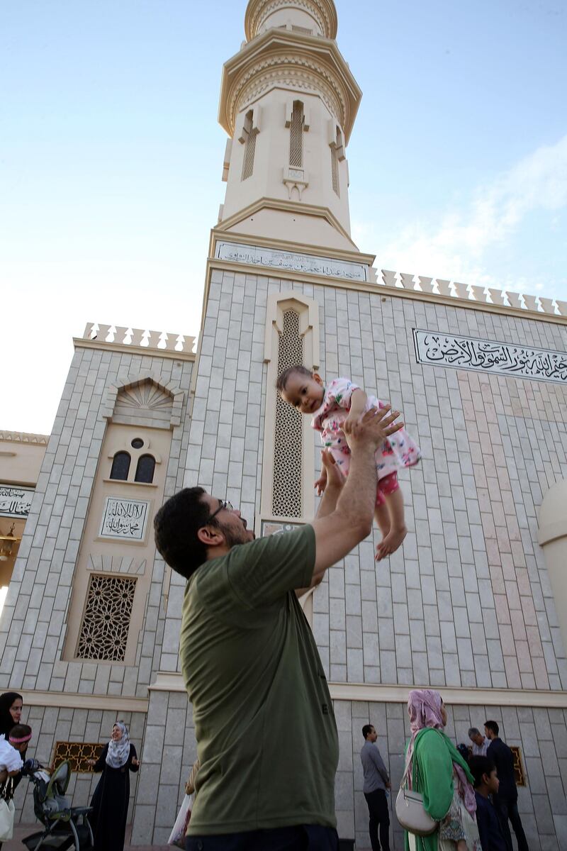 A Muslim man holds up a baby after the Eid al-Fitr prayer at Muscat's Al-Zawawi Mosque in the heart of the Omani capital. AFP
