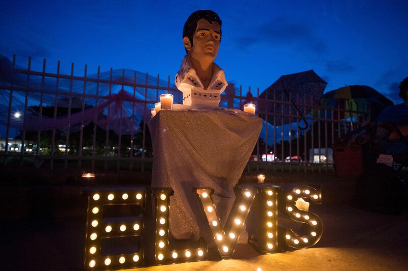 
                  A street memorial is lit during a candlelight vigil for Elvis Presley in front of Graceland, Presley's Memphis home, on Tuesday, Aug. 15, 2017, in Memphis, Tenn. Fans from around the world are at Graceland for the 40th anniversary of his death. Presley died Aug. 16, 1977. (AP Photo/Brandon Dill)
               